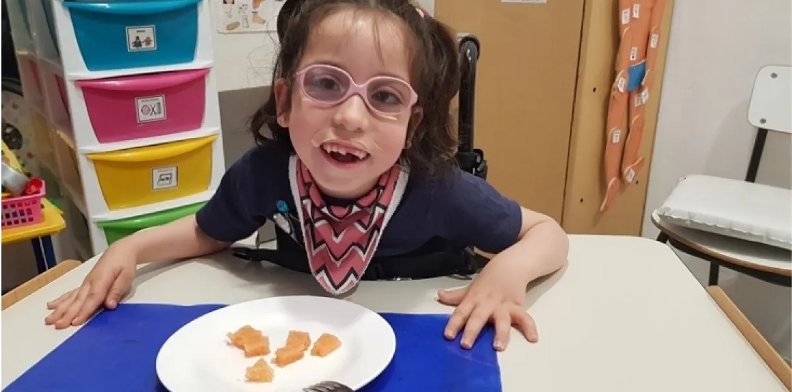 ¿Cómo alimentar a un niño con daño cerebral? 3 Niña con daño cerebral feliz con los alimentos servidos